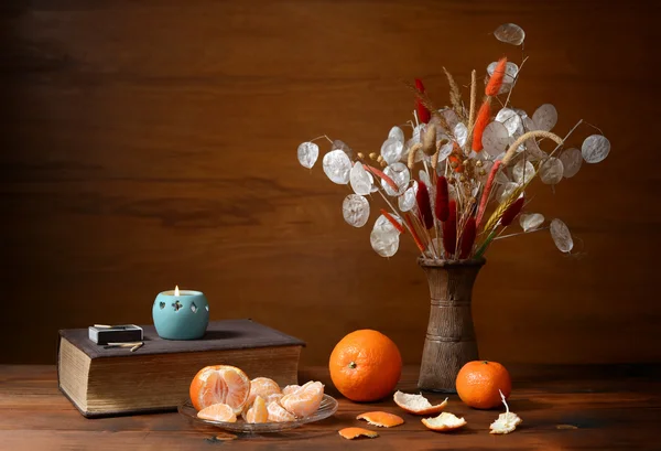 Laranjas frescas e flores secas em um vaso — Fotografia de Stock