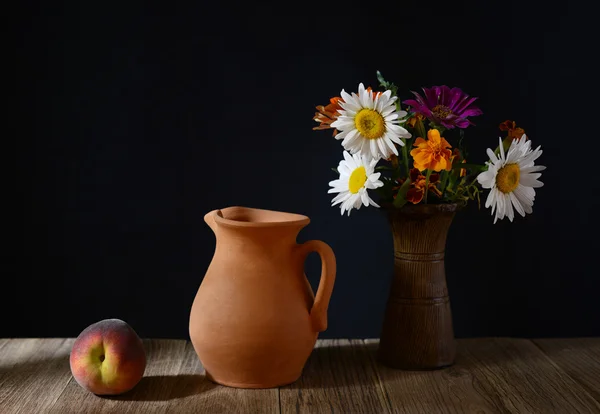 Ceramic carafe, peaches and flowers in a vase — Stock Photo, Image