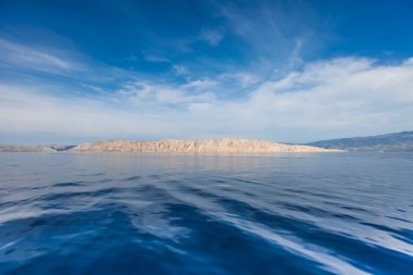 Hırvat adada mavi gökyüzü ve dalgalı deniz manzarası