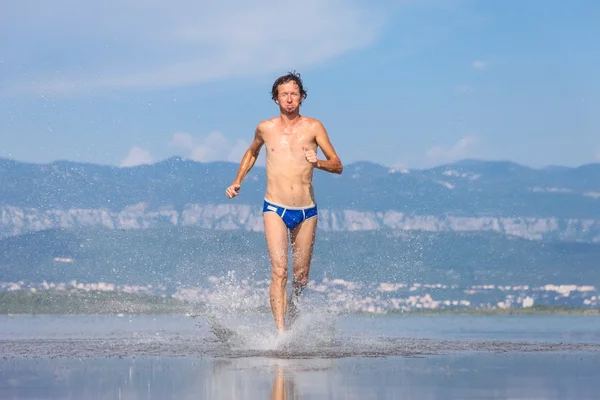 Homem corre através da praia — Fotografia de Stock