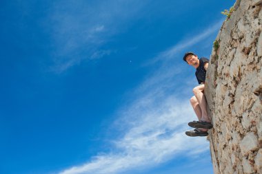 Duvarın kenarında oturan genç adam
