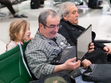 adam ve doha Uluslararası Havaalanı bekleme alanında açılan laptop bakarak küçük sarışın kız