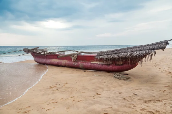 Hagyományos Srí Lanka-i horgászcsónak üres homokos strandon. — Stock Fotó