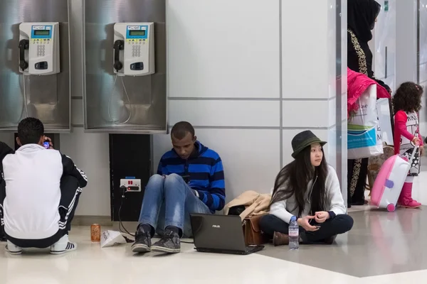 Jonge mensen zittend op de vloer en wachten op hun vlucht op de internationale luchthaven van doha — Stockfoto