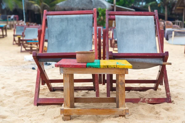 Twee lege rode ligstoelen aan zandstrand. — Stockfoto