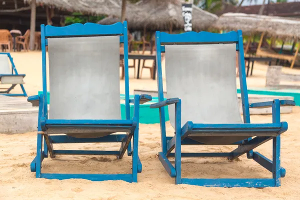 Twee lege blauwe ligstoelen aan zandstrand. — Stockfoto