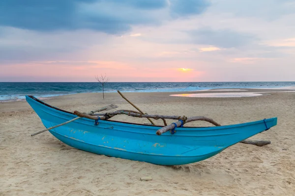 Traditional Sri Lankan fishing boat on empty sandy beach at sunset. Stock Picture