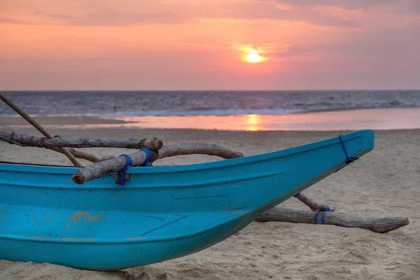 Traditional Sri Lankan fishing boat on empty sandy beach at sunset. Stock Photo