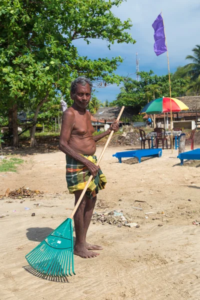 Helyi férfi takarítás beach műanyag gereblye. — Stock Fotó