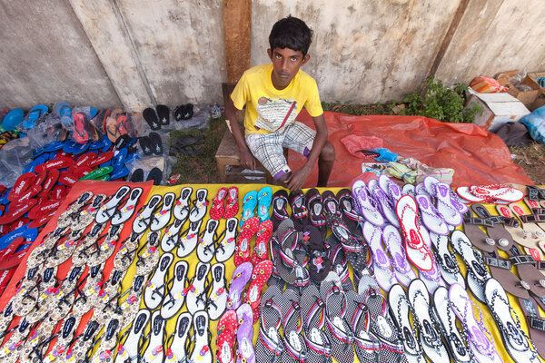 Молодой местный уличный торговец сандалиями
