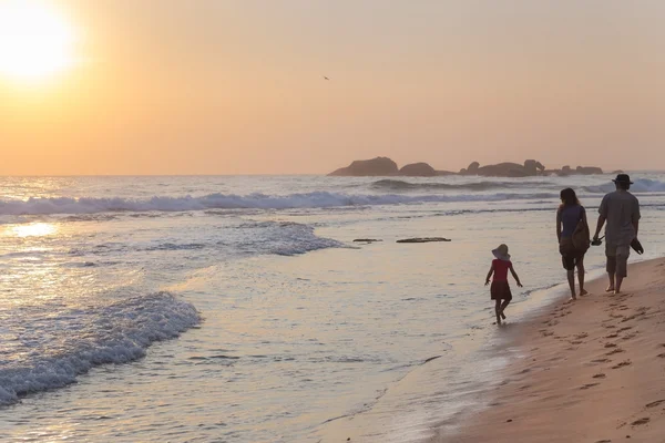 Familie spaziert bei Sonnenuntergang am Sandstrand — Stockfoto