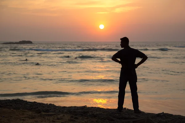 Silhuetten av en man på stranden vid solnedgången — Stockfoto