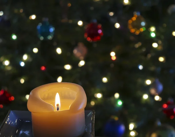 Una vela frente a un árbol de Navidad — Foto de Stock