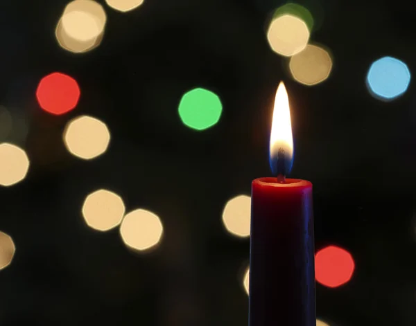 Uma vela de Natal vermelha com luzes embaçadas — Fotografia de Stock