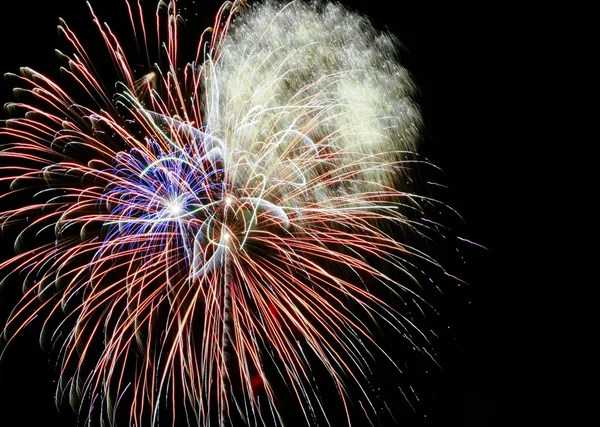 Um céu noturno cheio de fogos de artifício explosivos — Fotografia de Stock