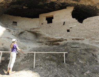 A Woman Examines Cave 2 at the Gila Cliff Dwellings clipart