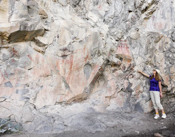 Žena poukazuje piktogramy v gila cliff byty — Stock fotografie