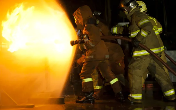 Brandweerlieden vallen een propaan brand tijdens een training. Stockfoto