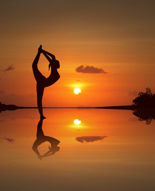 Yansıtılmış sunset Beach güzel yoga kız silüeti