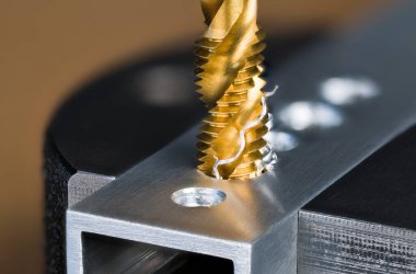 Spiral flüt çeliği ısırığı alüminyum profil deliğinde mengeneye sıkıştırılmış bir ip oluşturuyor. Titanyum kaplı altın kesme aleti ve bükülmüş cüce. Makine mühendisliğinde çalışan metal..
