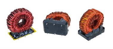 Beyaz panoramik arka planda izole edilmiş çeşitli elektronik toroidal bobinlerin yakın çekimi. Siyah epoksi reçineyle kaplanmış prizlere sarılı bakır telli kırmızı indüktörler. Elektroteknik bileşenler.