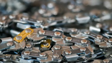 Güzel bulanık arkaplanı olan zincirli testere dokusu ve bokeh. Metal zincir zincirlerinin halkalarında keskin çelik dişlere yakın çekim. Elektrikli testere makinesi kılavuz çubuğu için profesyonel yedek parça.