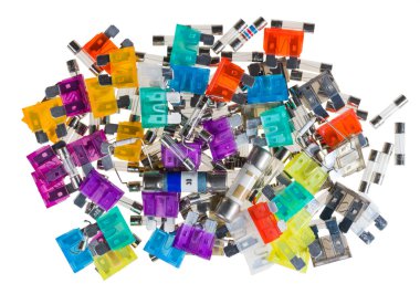 Electrical automotive or glass tube fuses in colored pile isolated on a white background. Closeup of safety devices for overcurrent protection a different type and size in electronics industry. E-waste.