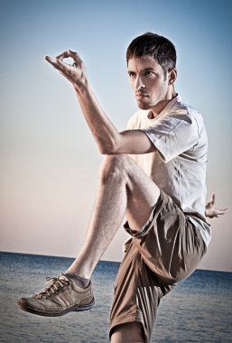 genç çekici bir adam sahilde Thai chi hareketleri yapma