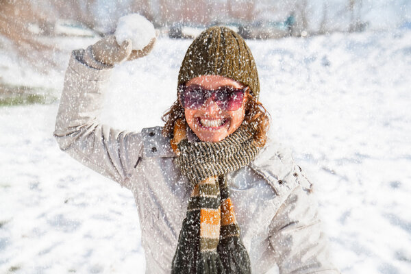 Happy young woman playing snowball fight