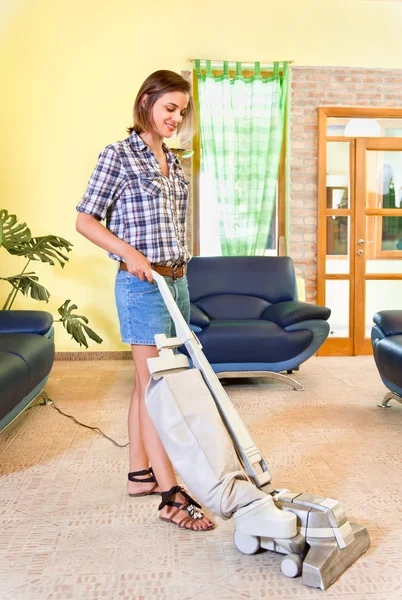 Jeune belle femme avec aspirateur à la maison . — Photo