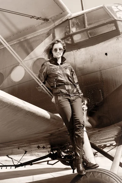 Красива дівчина в чорній куртці стоїть на військовому літаку . — стокове фото