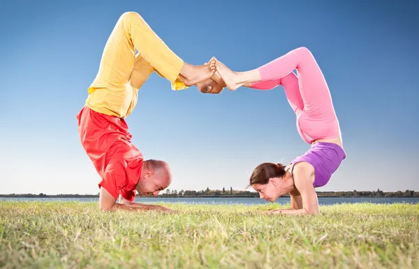 Yoga couple, man and woman doing Vrschikasana scorpion pose — Stock Photo, Image