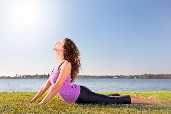 Beautiful young woman doing stretching exercise on green grass. — Stock Photo, Image