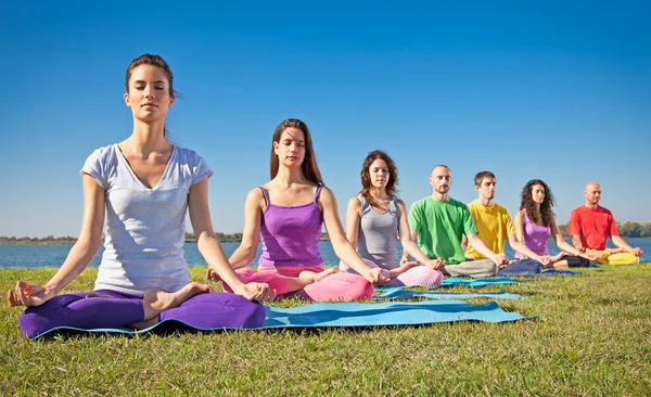 Grupo de jovens têm meditação na aula de ioga . Fotos De Bancos De Imagens