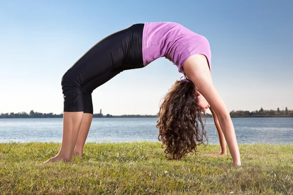 Krásná mladá žena, která dělá jóga cvičení na zelené trávě — Stock fotografie