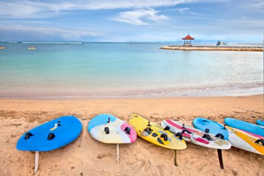 Surf boards on idyllic tropical sand Nusa Dua beach, Bali clipart