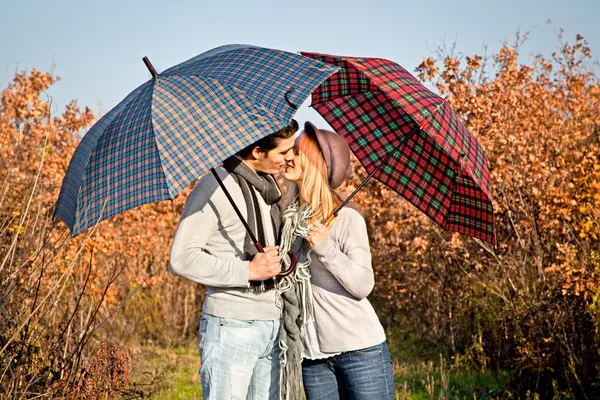 Coppia baci sotto gli ombrelloni nel parco . — Foto Stock