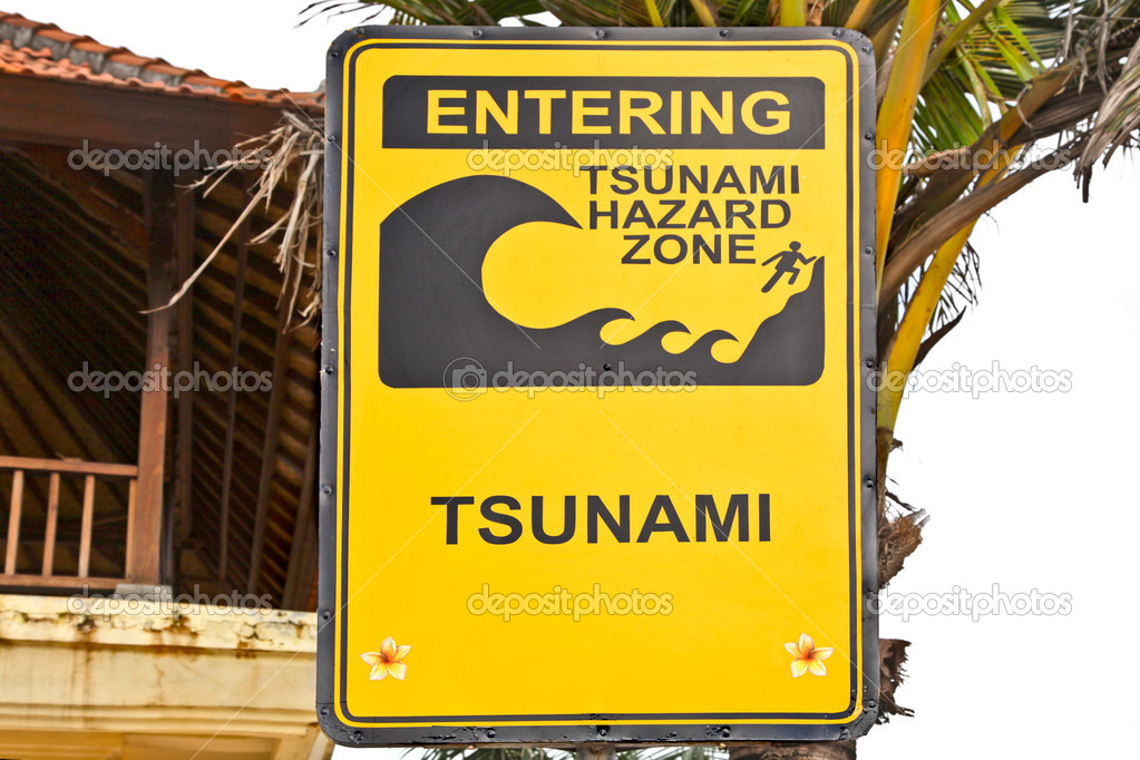 Big yellow tsunami sign on a wooden post on beach in Bali
