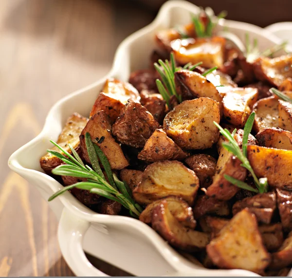 Batatas de erva de alecrim em assadeira branca perto . — Fotografia de Stock