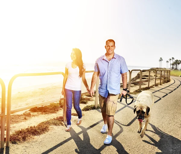 Couple walking pet dog by the ocean — Stock Photo, Image