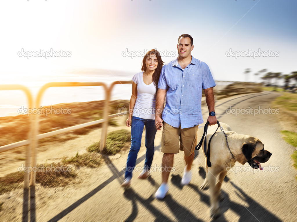 Couple walking pet dog by the ocean