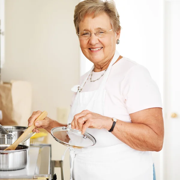 Happy grandmother cooking in kitchen — Stock Photo, Image