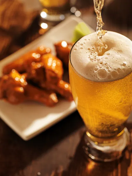 Pouring beer with chicken wings — Stock Photo, Image