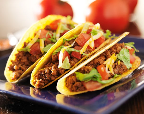 Three beef tacos with cheese, lettuce and tomatoes — Stock Photo, Image