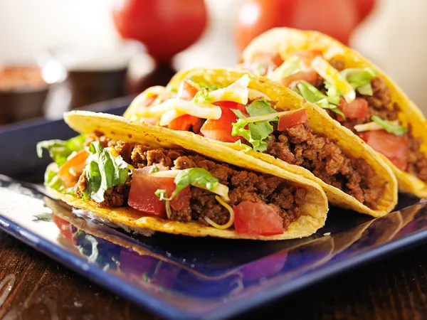 Three beef tacos with cheese, lettuce and tomatoes — Stock Photo, Image