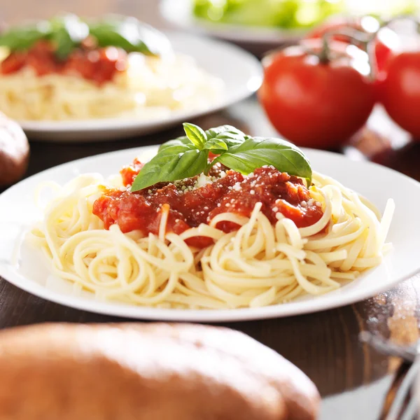 Plate of spaghetti with basil garnish. — Stockfoto