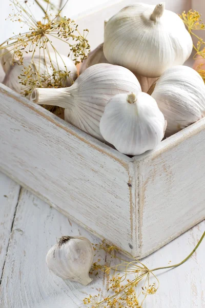 Knoblauch in einer schäbigen Holzkiste auf dem Küchentisch — Stockfoto