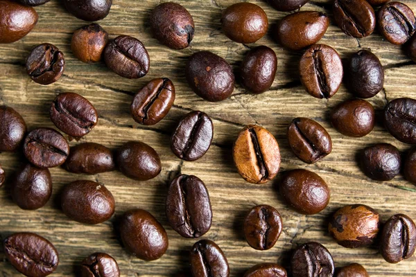 Coffee beans on old worn board — Stock Photo, Image