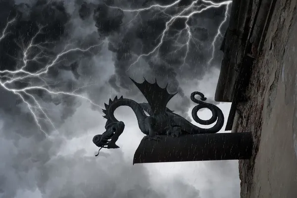 Frightening chimera on the facade of the old castle under thunderclouds and lightning — Stock Photo, Image