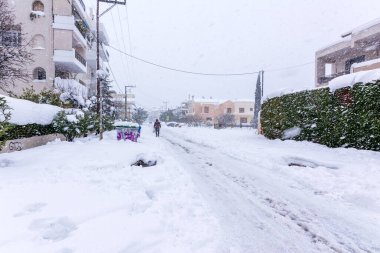 Atina 'da bir kar fırtınası sırasında, Yunanistan' ın başkenti Avrupa 'da, Vrilissia bölgesinde kar yağdı. Sokakta bir adam yürüyor..